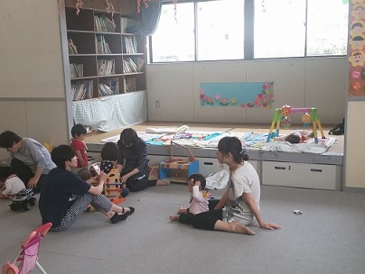 松原学童保育所の室内で大人と子供が座って遊んでいる
