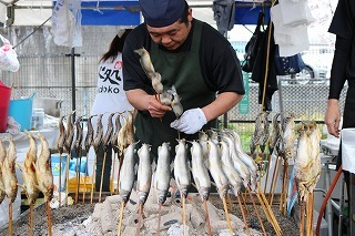 エプロンをした人が魚を焼いている