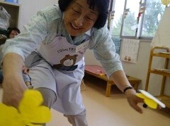 先生がちょうちょの折り紙を持って歌っている様子