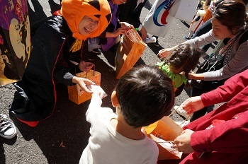 かぼちゃの着ぐるみをつけてお菓子を配っている様子