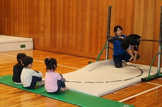 コーチが子供に鉄棒の指導をしている