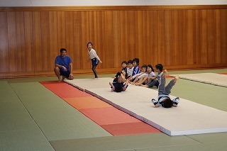 コーチが子供にマット運動の指導をしている